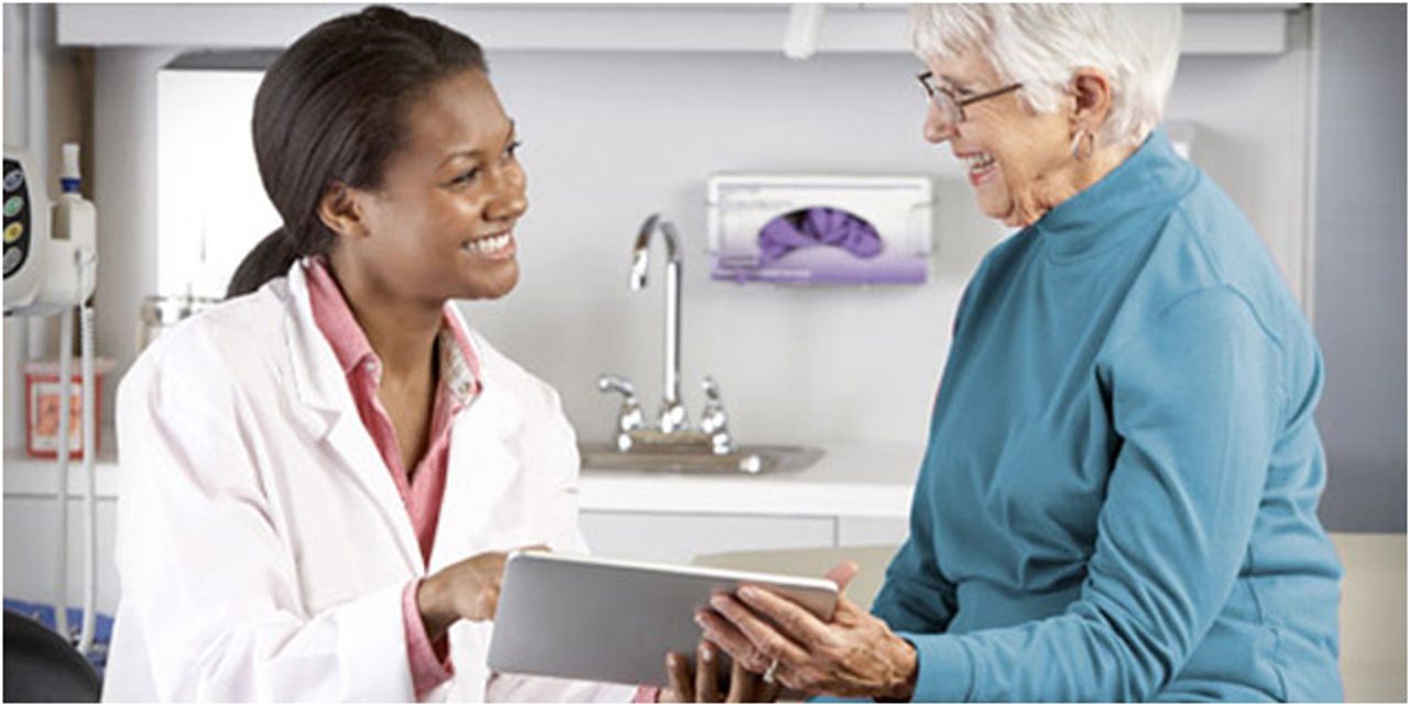 A doctor explains a concept to patient by showing her content on a tablet.